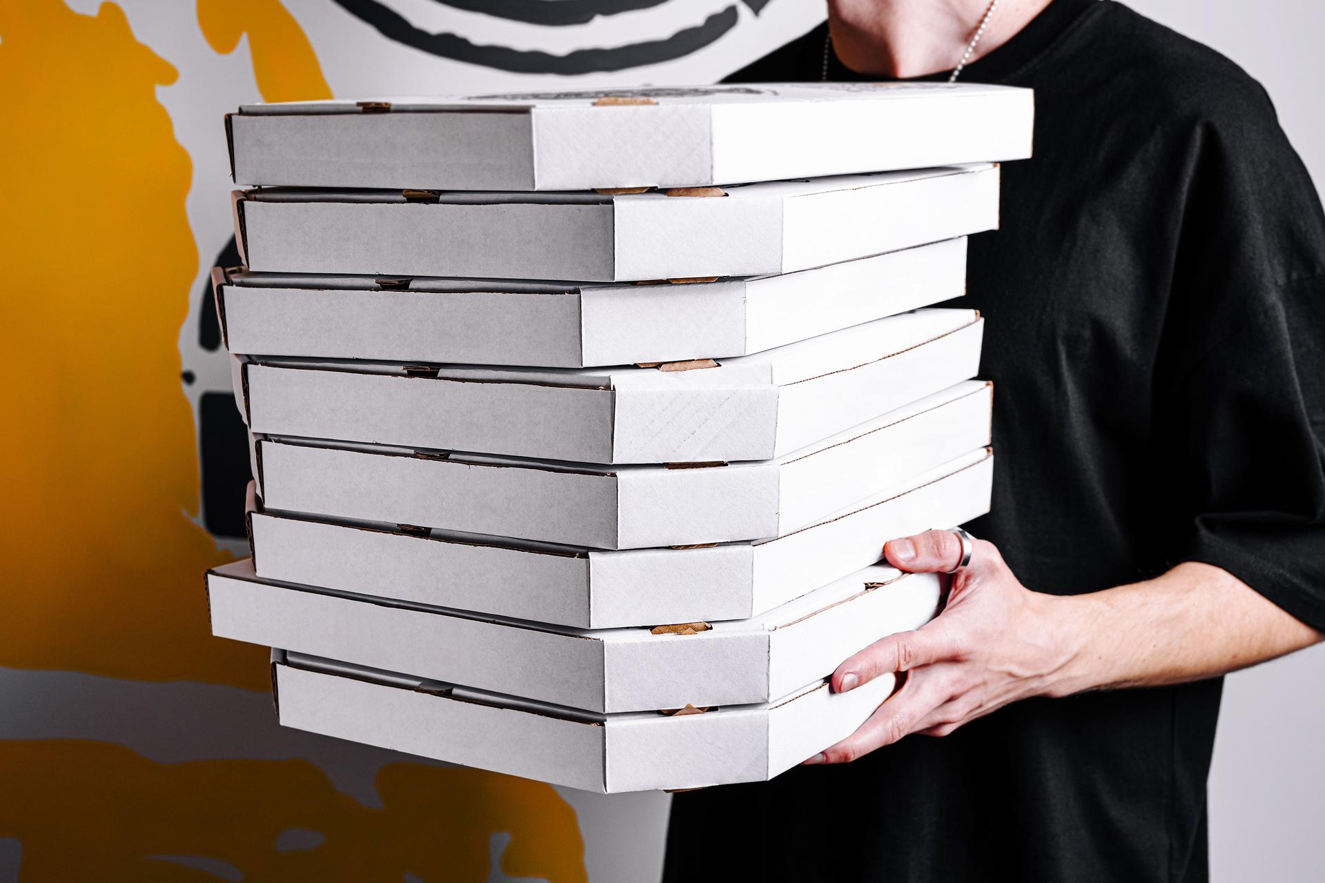 Group of pizza boxes being carried by a person against a colorful background